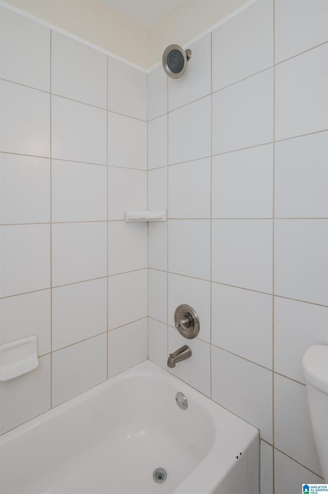 bathroom featuring tiled shower / bath and toilet