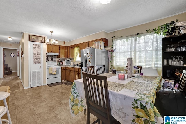 dining space with a notable chandelier, light tile patterned flooring, a textured ceiling, and crown molding