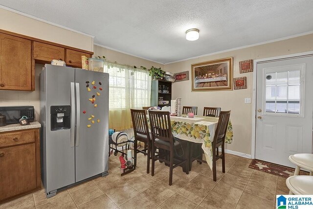 dining area featuring light tile patterned flooring, a textured ceiling, and ornamental molding