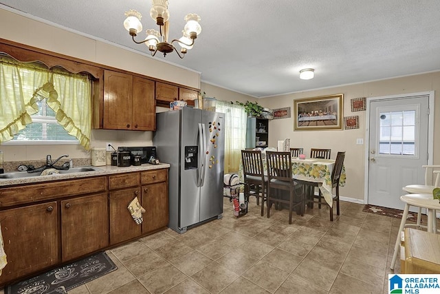 kitchen featuring a textured ceiling, a chandelier, stainless steel fridge with ice dispenser, light tile patterned floors, and sink