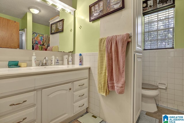 bathroom featuring tile patterned floors, tile walls, vanity, and toilet