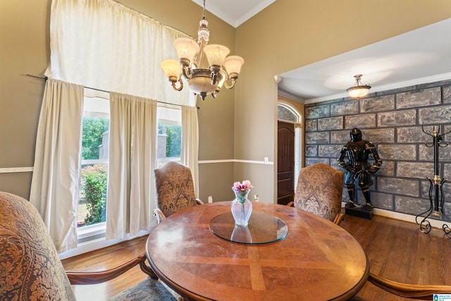 dining area with wood-type flooring, ornamental molding, and an inviting chandelier