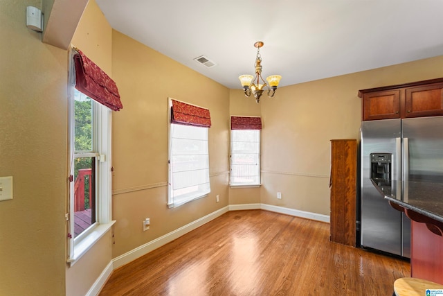 unfurnished dining area with hardwood / wood-style flooring, a wealth of natural light, and a chandelier