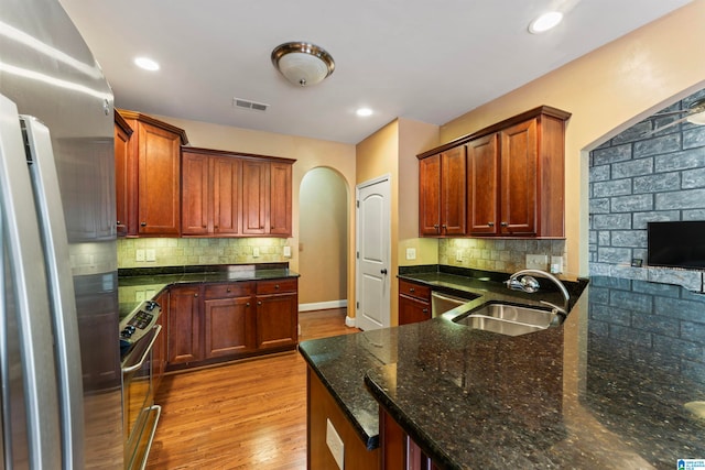 kitchen featuring sink, stainless steel appliances, light hardwood / wood-style floors, and tasteful backsplash