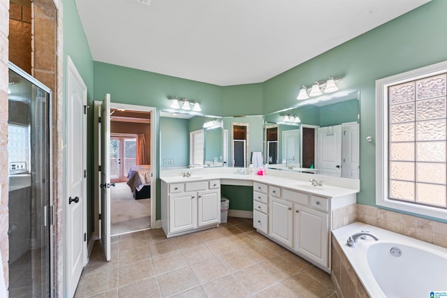 bathroom featuring vanity, tiled tub, plenty of natural light, and tile patterned flooring