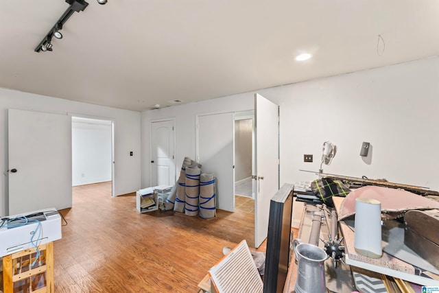 workout area with rail lighting and light hardwood / wood-style floors