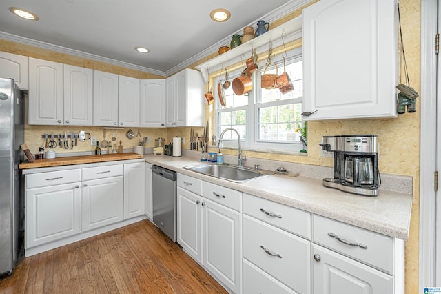 kitchen with wood-type flooring, appliances with stainless steel finishes, crown molding, and white cabinetry