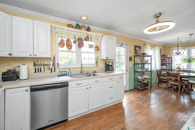 kitchen with sink, white cabinetry, hanging light fixtures, hardwood / wood-style floors, and stainless steel dishwasher