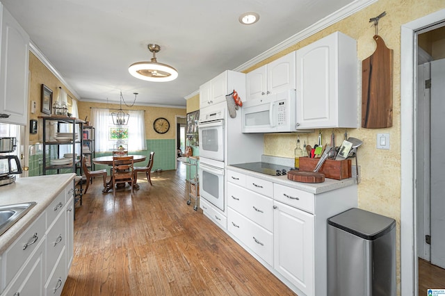 kitchen with light hardwood / wood-style floors, white cabinetry, white appliances, pendant lighting, and crown molding