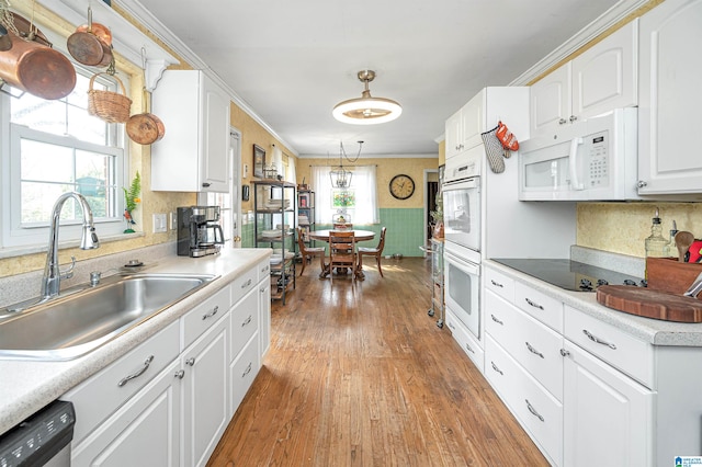 kitchen featuring white cabinetry, white appliances, light wood-type flooring, ornamental molding, and sink