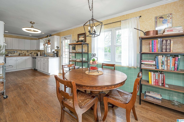 dining area with wood-type flooring, a chandelier, sink, and crown molding