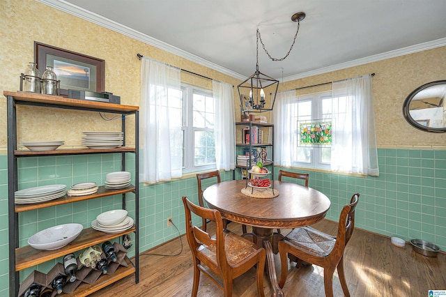 dining room with ornamental molding, tile walls, hardwood / wood-style flooring, and an inviting chandelier