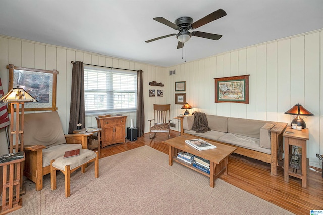 living room featuring wood walls, ceiling fan, and hardwood / wood-style flooring