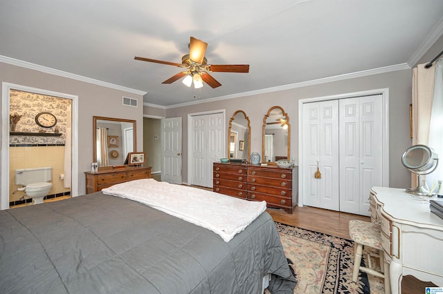 bedroom with ensuite bath, hardwood / wood-style floors, crown molding, two closets, and ceiling fan