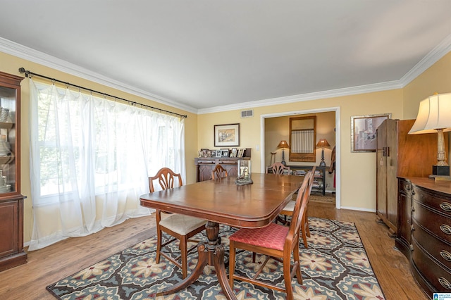 dining area with light wood-type flooring and crown molding