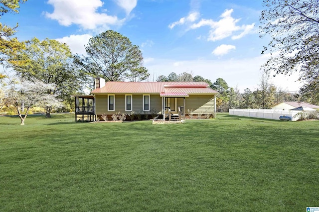 back of property with metal roof, fence, a sunroom, a yard, and a chimney