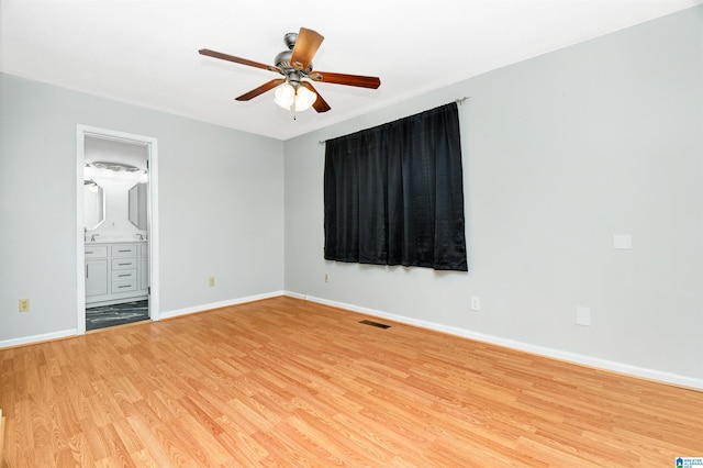 unfurnished bedroom featuring connected bathroom, light wood-style flooring, a ceiling fan, visible vents, and baseboards