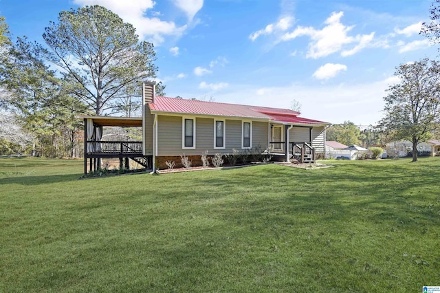 view of front of home with a front yard, covered porch, metal roof, and a chimney