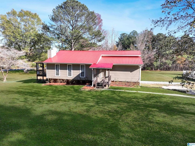 view of front facade with metal roof, a front lawn, and a chimney