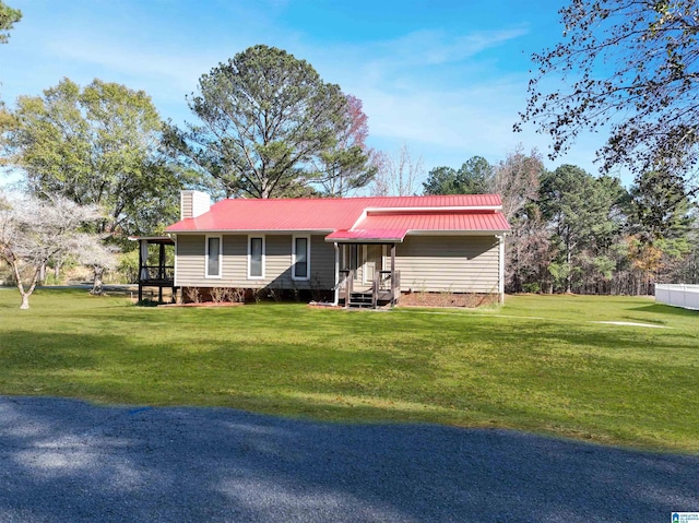 ranch-style house with a chimney, metal roof, and a front yard