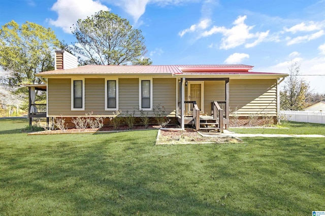 view of front of house featuring metal roof, a front lawn, and a chimney