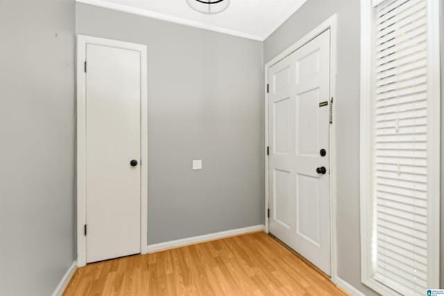 foyer with baseboards, light wood-style floors, a healthy amount of sunlight, and crown molding