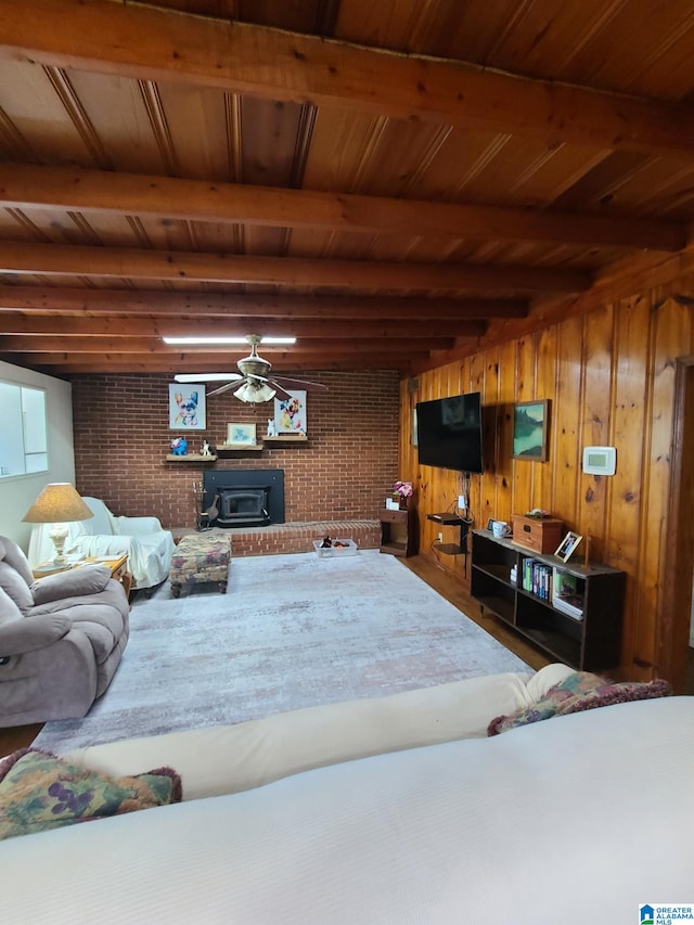 living room with ceiling fan, wooden ceiling, a brick fireplace, and brick wall