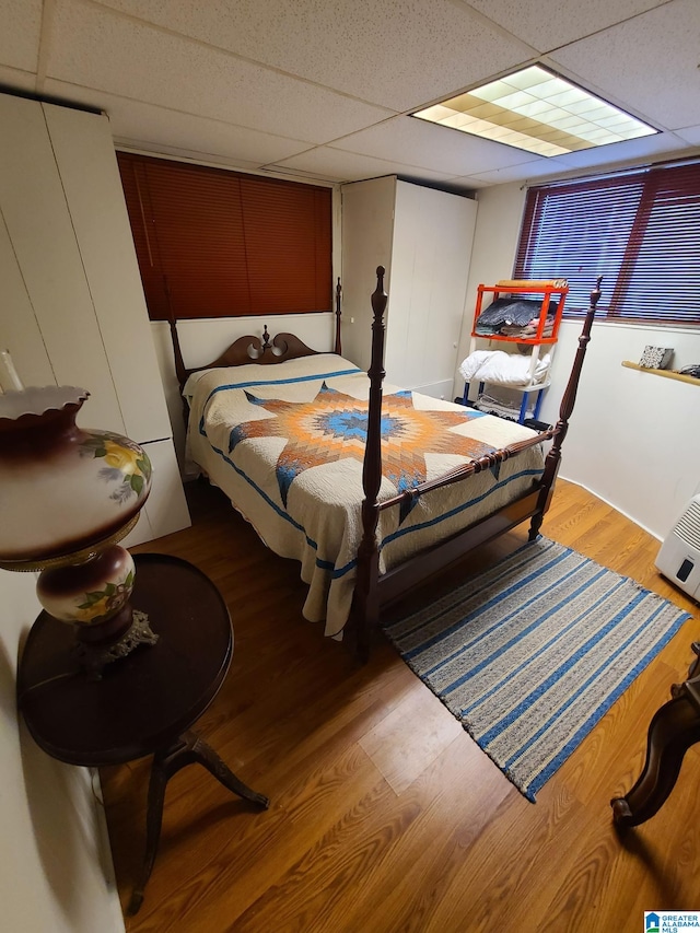 bedroom with a paneled ceiling and light hardwood / wood-style floors