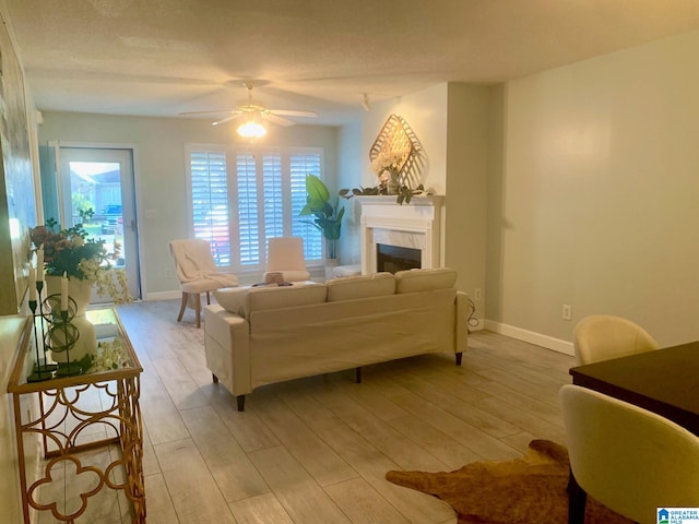 living room featuring ceiling fan, a textured ceiling, and light wood-type flooring