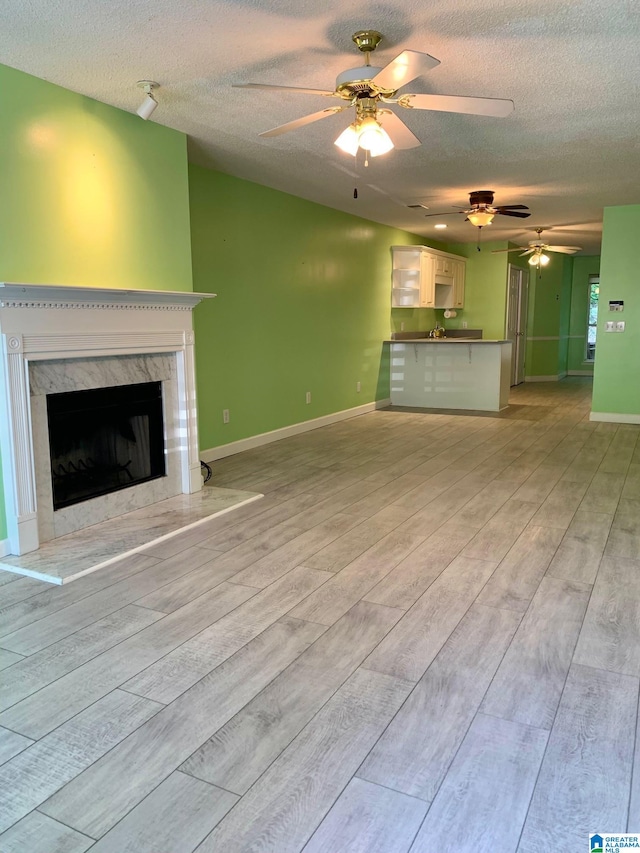 unfurnished living room with a textured ceiling, light hardwood / wood-style floors, and a premium fireplace