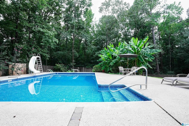 view of swimming pool with a water slide and a patio area