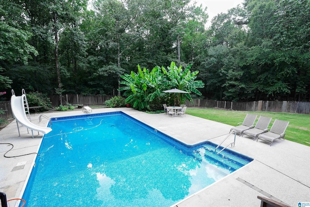 view of swimming pool with a lawn, a water slide, a diving board, and a patio area