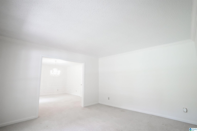 carpeted empty room with a chandelier and a textured ceiling