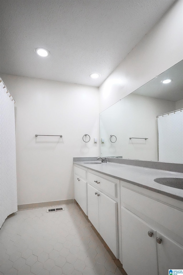 bathroom featuring double sink vanity, a textured ceiling, and tile patterned floors