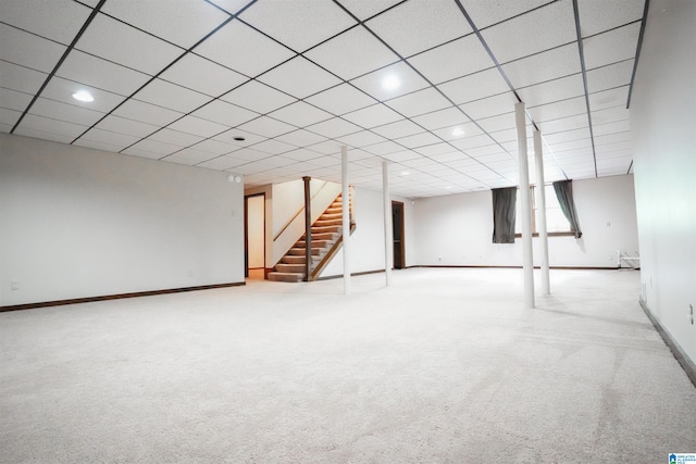 basement with a drop ceiling and light carpet