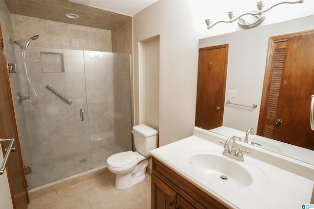 bathroom featuring a shower with door, vanity, tile patterned flooring, and toilet