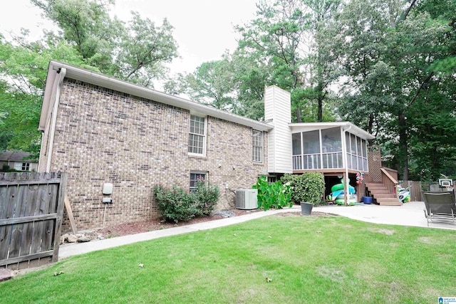 rear view of property with central AC, a sunroom, and a yard