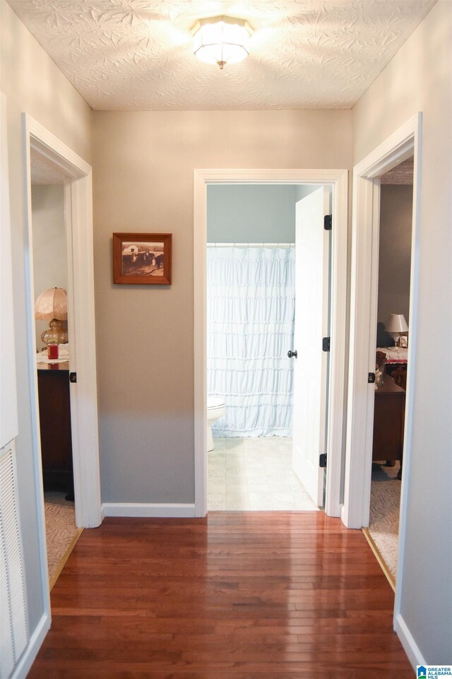 corridor featuring a textured ceiling and carpet