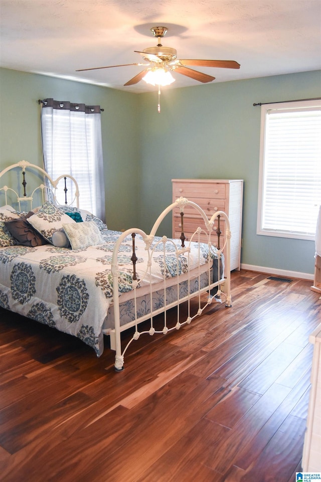 bedroom with ceiling fan, wood-type flooring, and multiple windows