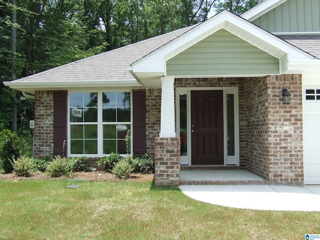 view of exterior entry featuring covered porch and a yard