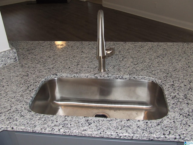 details with sink, hardwood / wood-style flooring, and light stone countertops