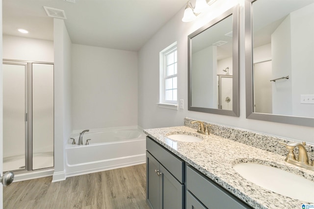 bathroom with dual bowl vanity, hardwood / wood-style floors, and separate shower and tub