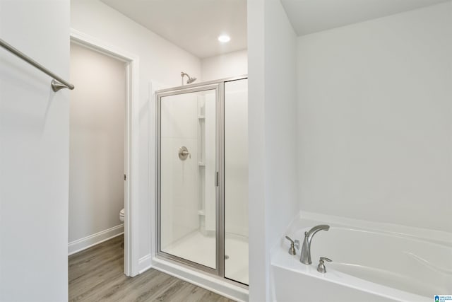 bathroom with toilet, plus walk in shower, and hardwood / wood-style floors