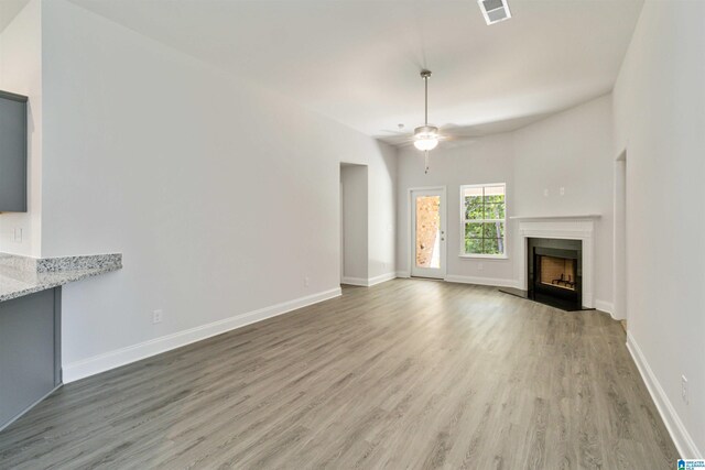 unfurnished living room featuring ceiling fan and hardwood / wood-style flooring