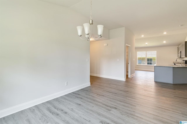 interior space featuring a notable chandelier, lofted ceiling, sink, and light hardwood / wood-style floors