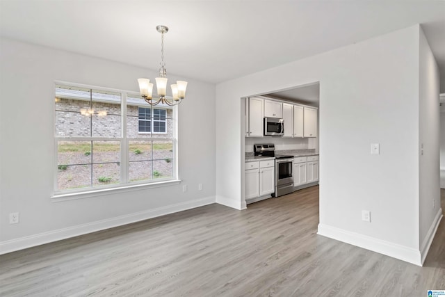 unfurnished dining area featuring light wood-type flooring and an inviting chandelier