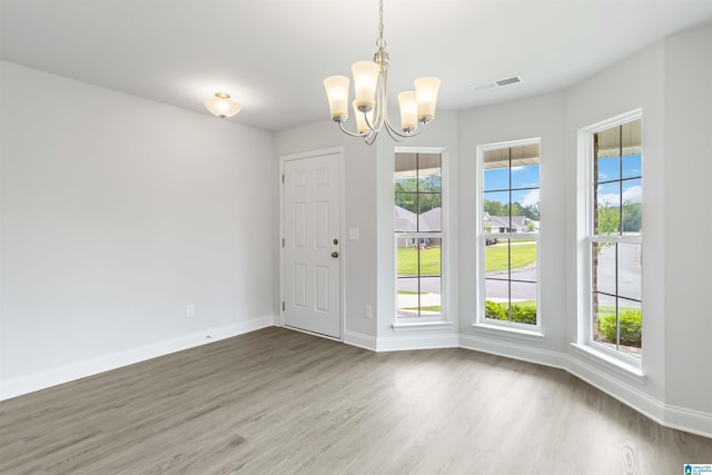 spare room with wood-type flooring and a notable chandelier