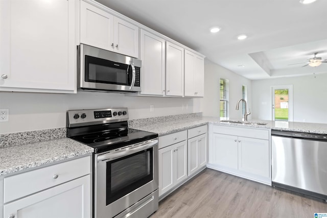 kitchen featuring light stone counters, stainless steel appliances, white cabinetry, and sink