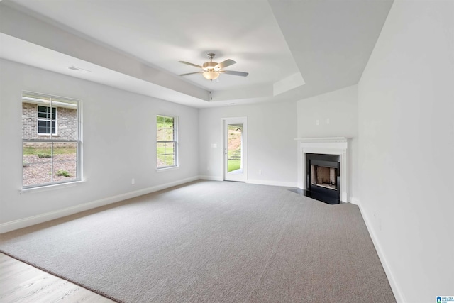 unfurnished living room featuring ceiling fan and a tray ceiling