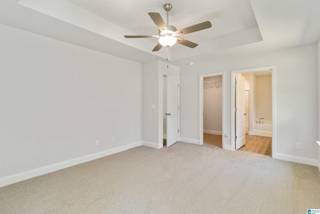 unfurnished bedroom with ceiling fan, ensuite bathroom, and light carpet